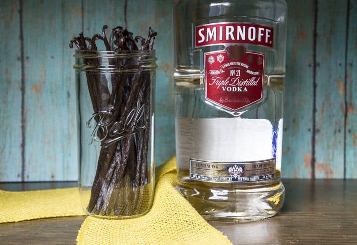 Vanilla beans in a mason jar next to a large bottle of vodka