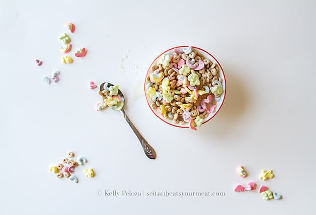 Bowl of Vegan Lucky Charms on white table with spoonful of cereal next to bowl