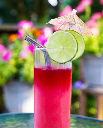 Pink cocktail on outdoor table with flowers