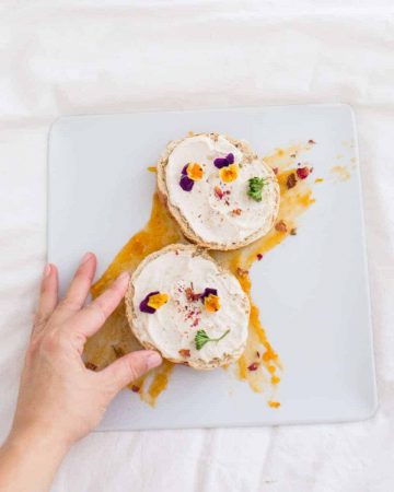 Bagels with vegan cashew cream cheese with edible flower garnish