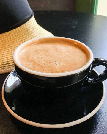 Cafe latte on table with hat in background