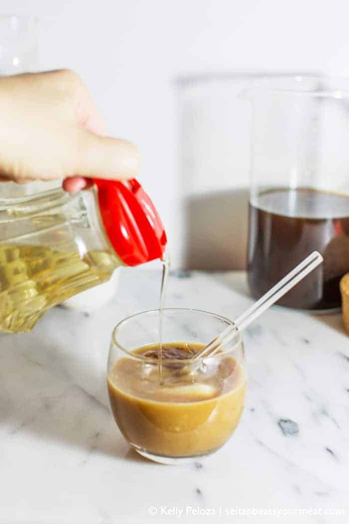 Hand pouring lavender simple syrup into iced coffee