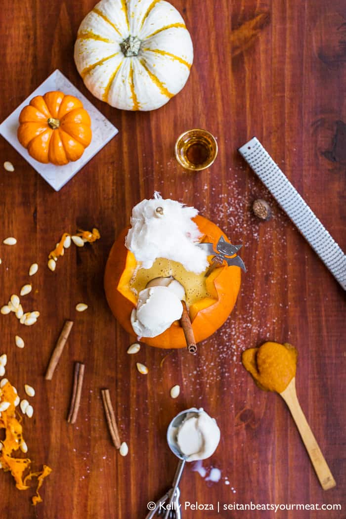 Overhead image of pumpkin spice milkshake served in pie pumpkin surrounded with spices and fall decor