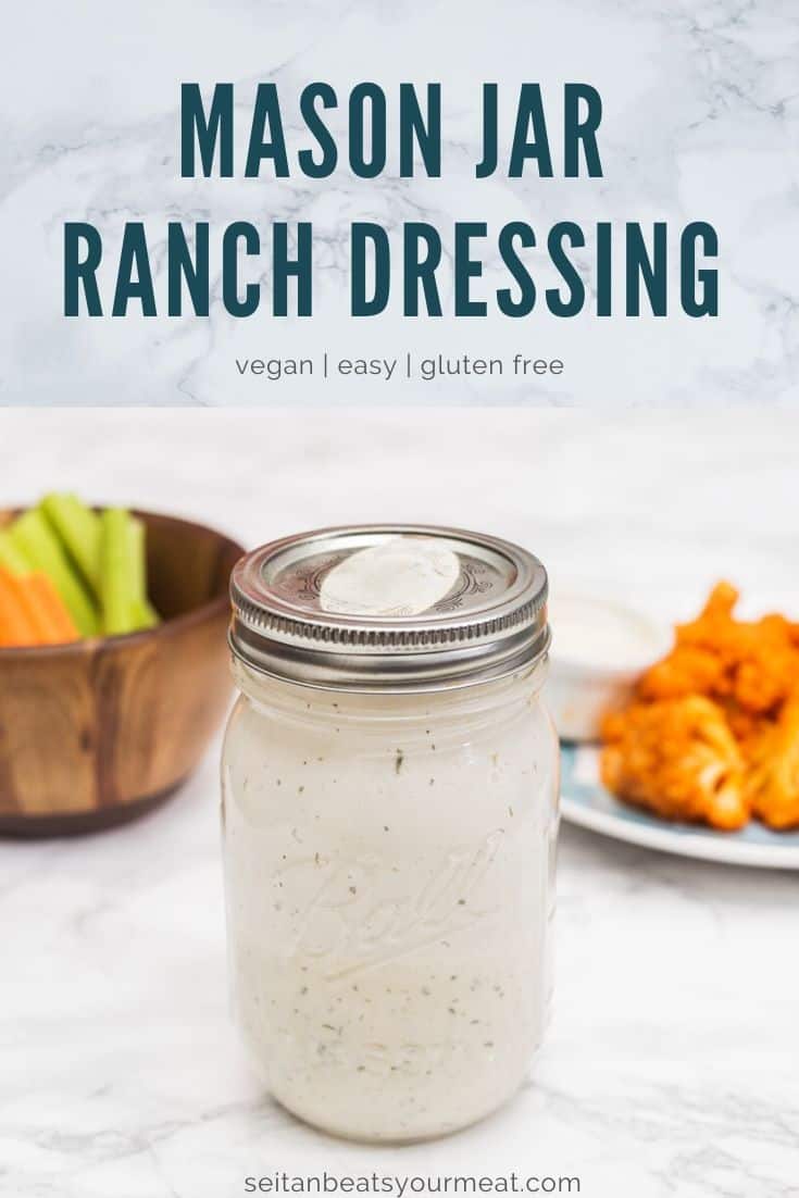 Mason jar of ranch dressing with plates of food in background