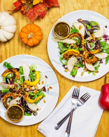 Overhead image of fall salads with pumpkins and pears surrounding the plates
