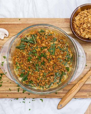 Overhead image of green bean casserole on cutting board surrounded by ingredients