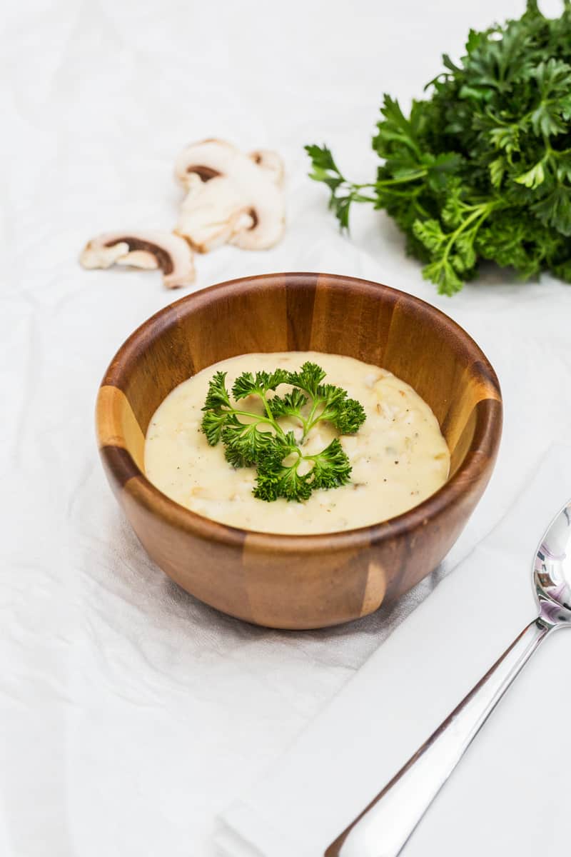 Cream of mushroom soup in a wooden bowl with mushrooms and parsley