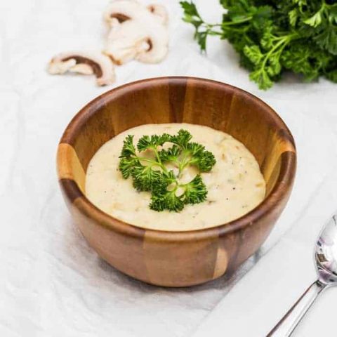 Cream of mushroom soup in a wooden bowl with mushrooms and parsley