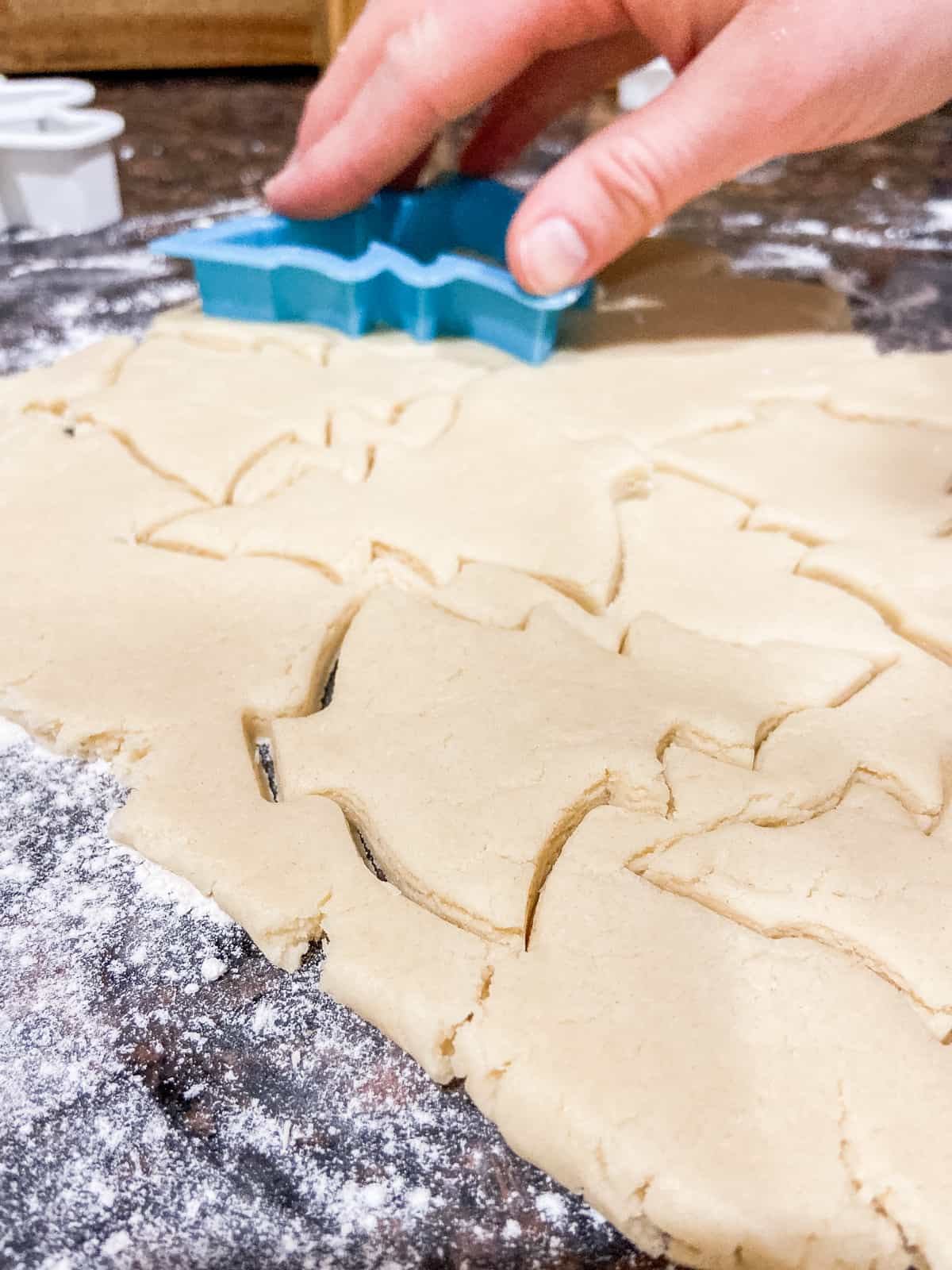 Rolled out sugar cookie dough with Christmas trees cut out of dough