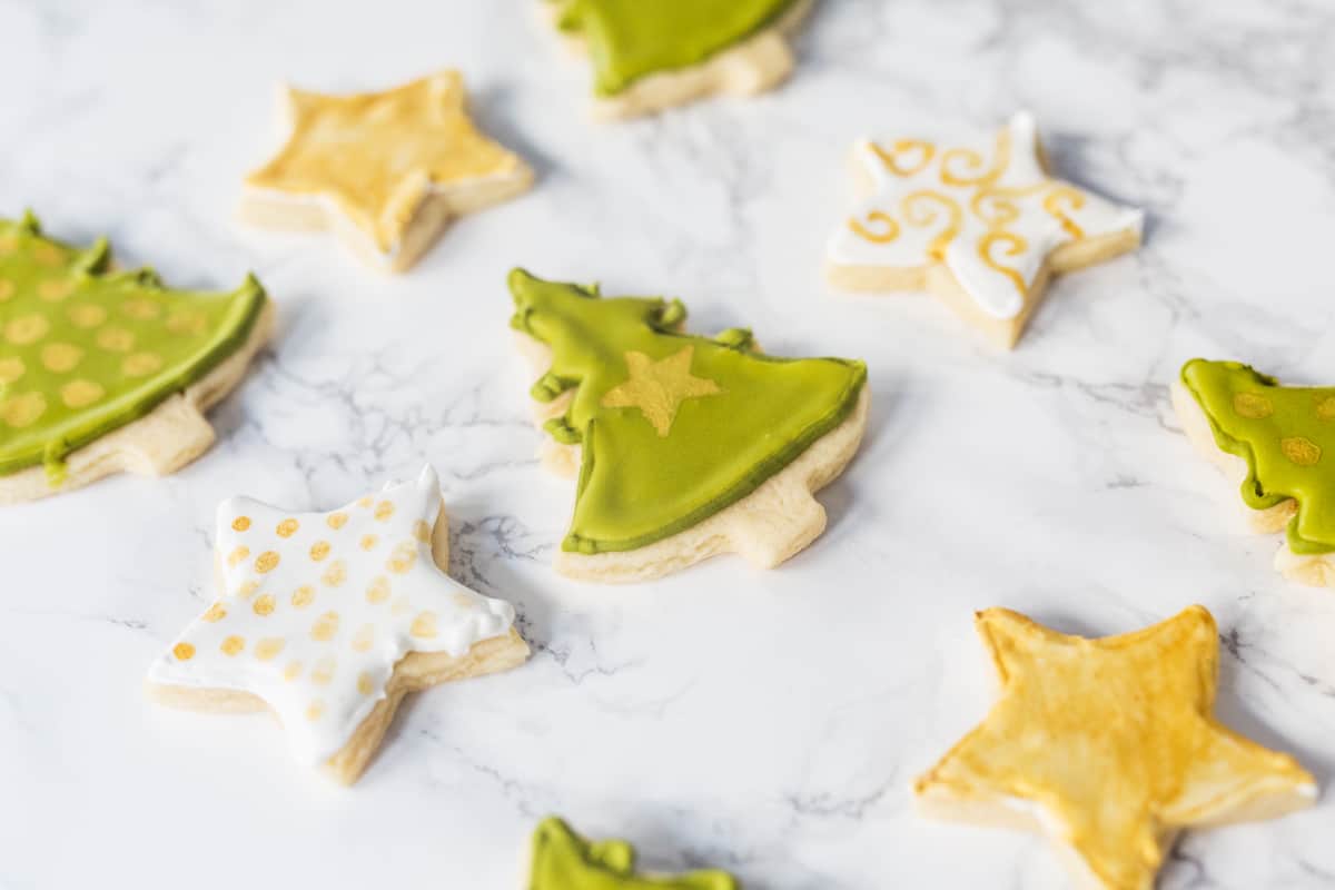 Decorated Christmas tree and star-shaped sugar cookies on marble surface