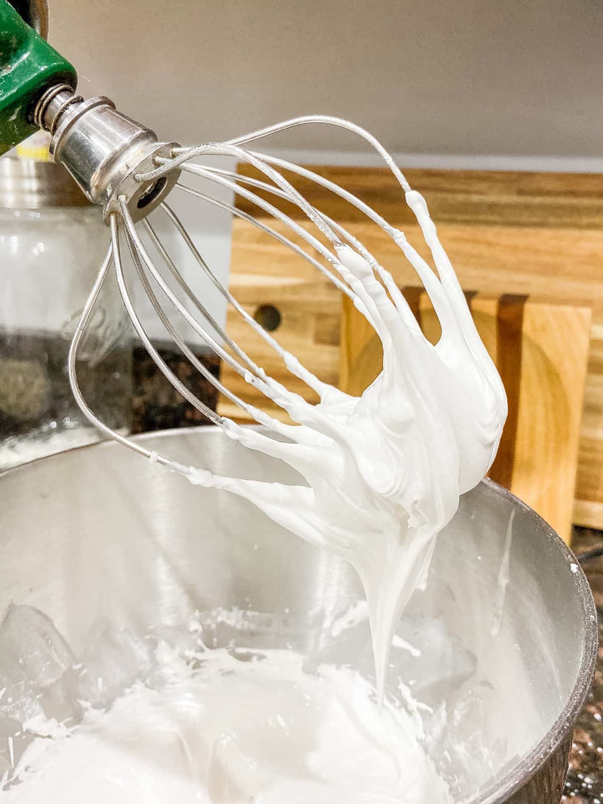 Balloon whisk on stand mixer with royal icing to show consistency of icing