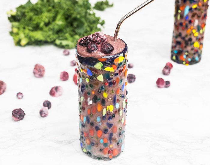 Blueberry avocado smoothie in colorful glass on marble surface