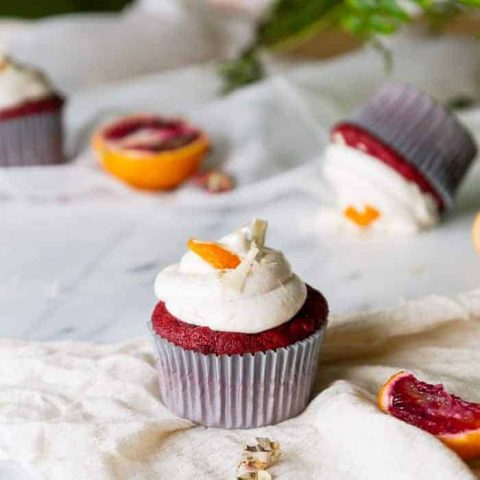 Red velvet cupcakes with frosting on marble background with blood orange slices