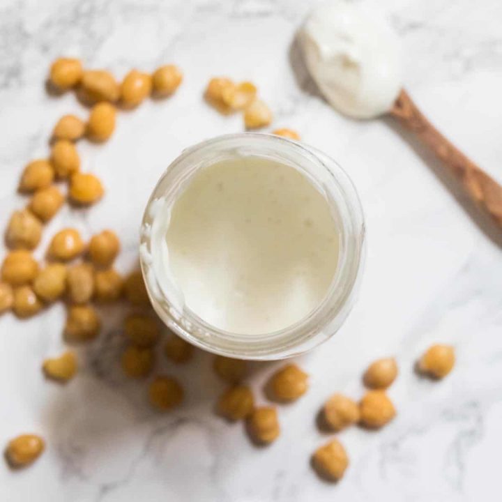 Mayonnaise in glass jar surrounded by chickpeas