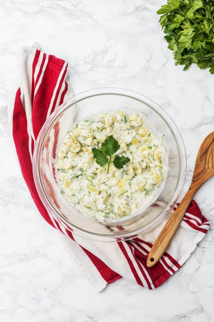 Large bowl of potato salad with wooden spoon and dish towel