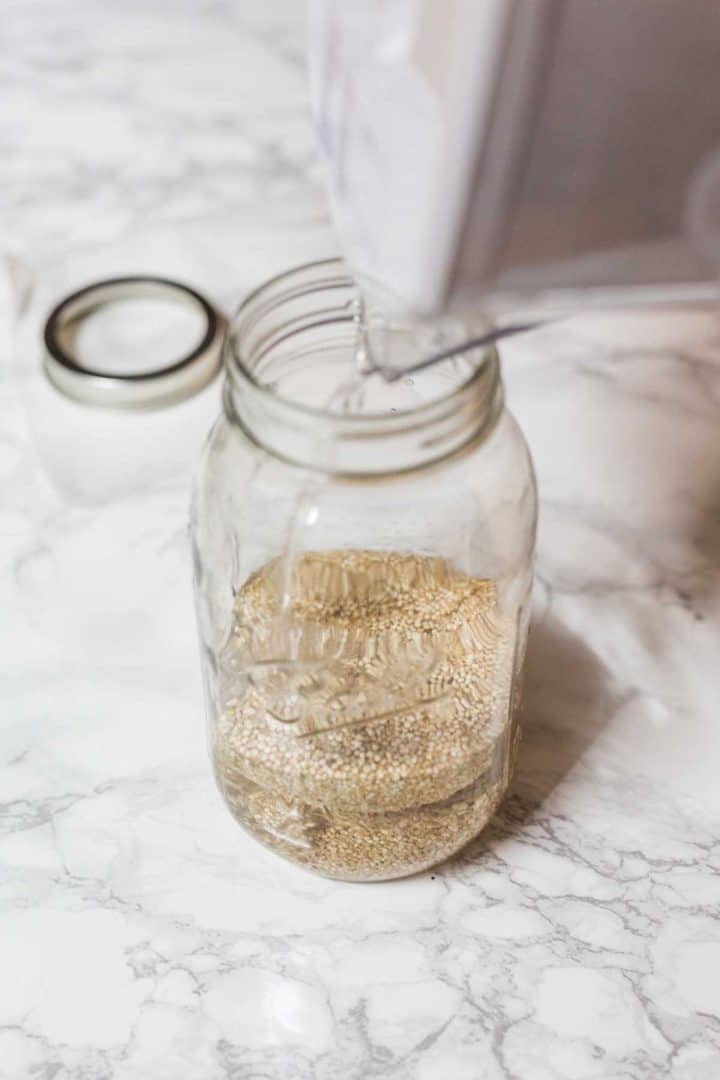 Water being poured into glass jar with quinoa