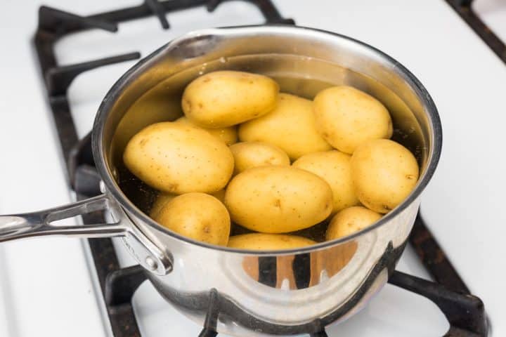 Pot full of unpeeled potatoes and water on stovetop