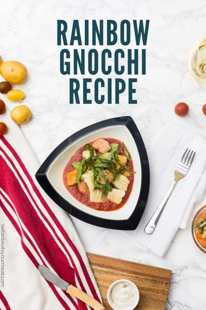Bowl of gnocchi with tomato sauce in table setting with text "Rainbow Gnocchi Recipe"