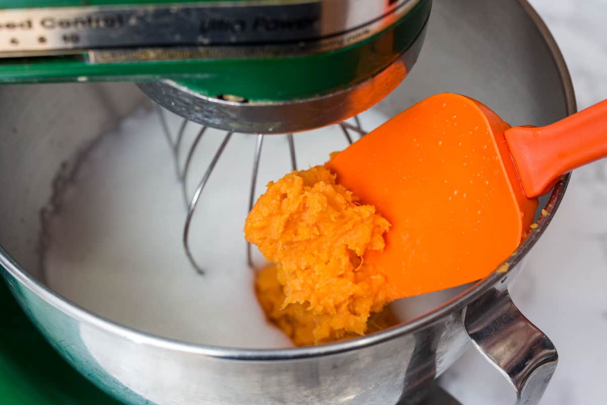 Spatula adding mashed sweet potato to Kitchenaid mixer