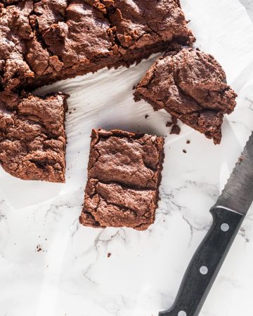 Cut brownies and crumbs on white marble counter with bread knife
