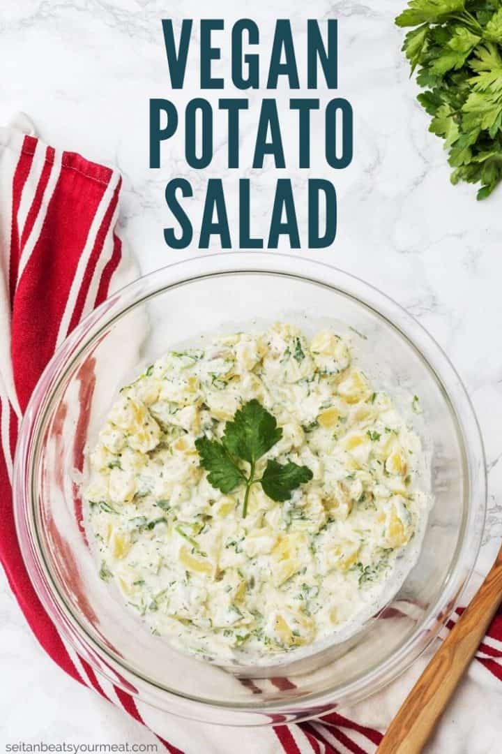 Large bowl of potato salad with wooden spoon and dish towel with text "Vegan Potato Salad"