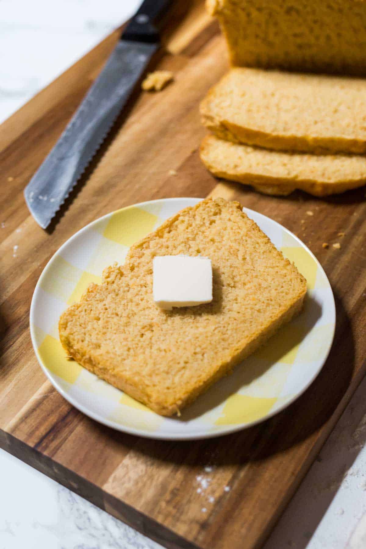 Slice of bread with pat of butter on plate on cutting board