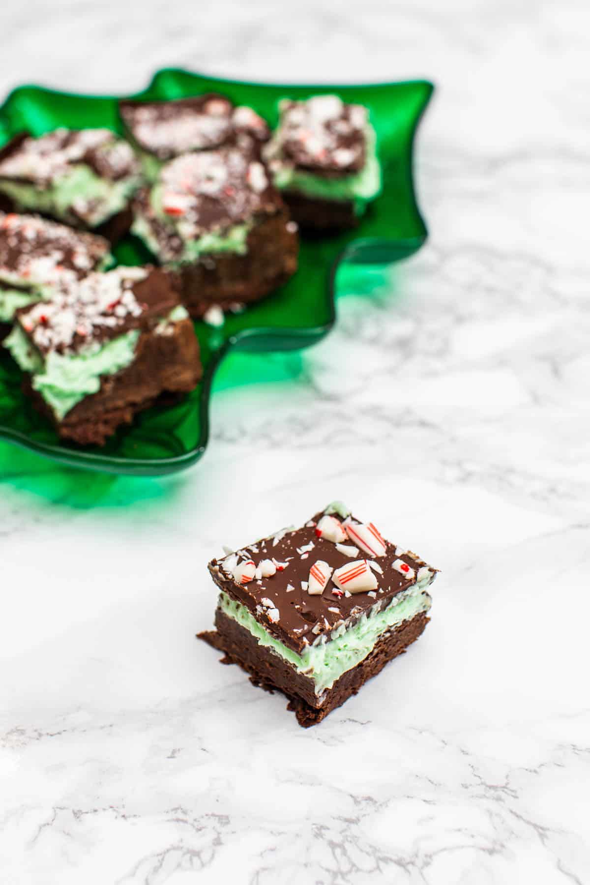 Chocolate peppermint cream bar with green tray of bars in the background