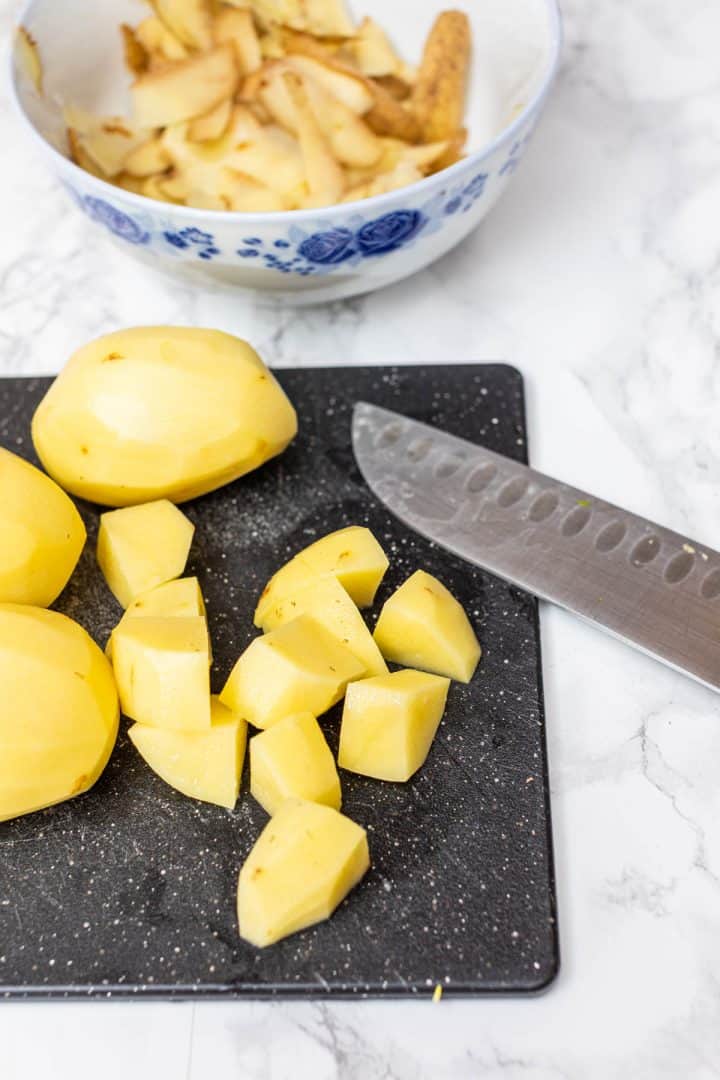 Peeled and chopped potatoes on cutting board with knife