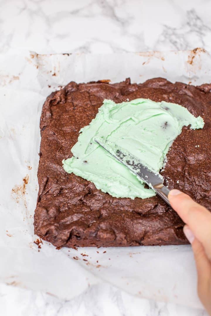 Spreading green frosting on tray of brownies