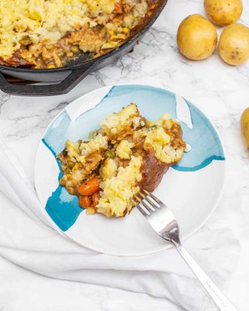 Plate of shepherd's pie with cast iron pan in background