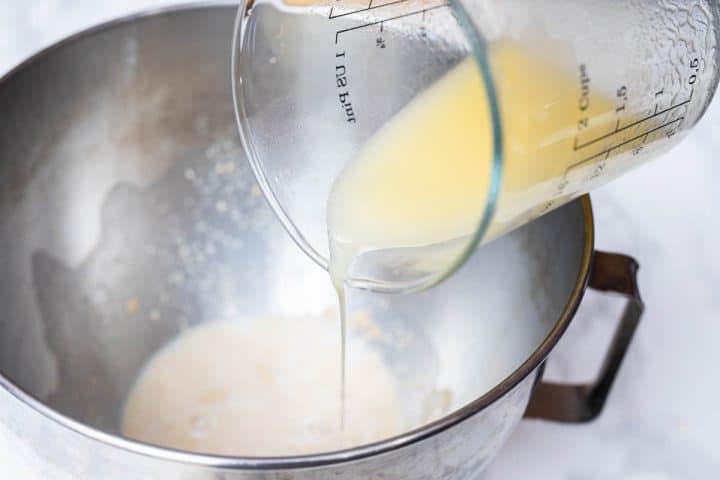 Measuring cup pouring vegan butter in large bowl