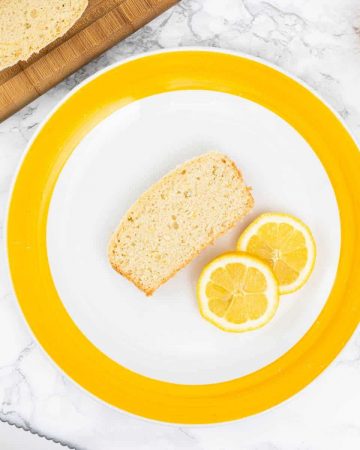 Slice of lemon loaf on yellow and white plate