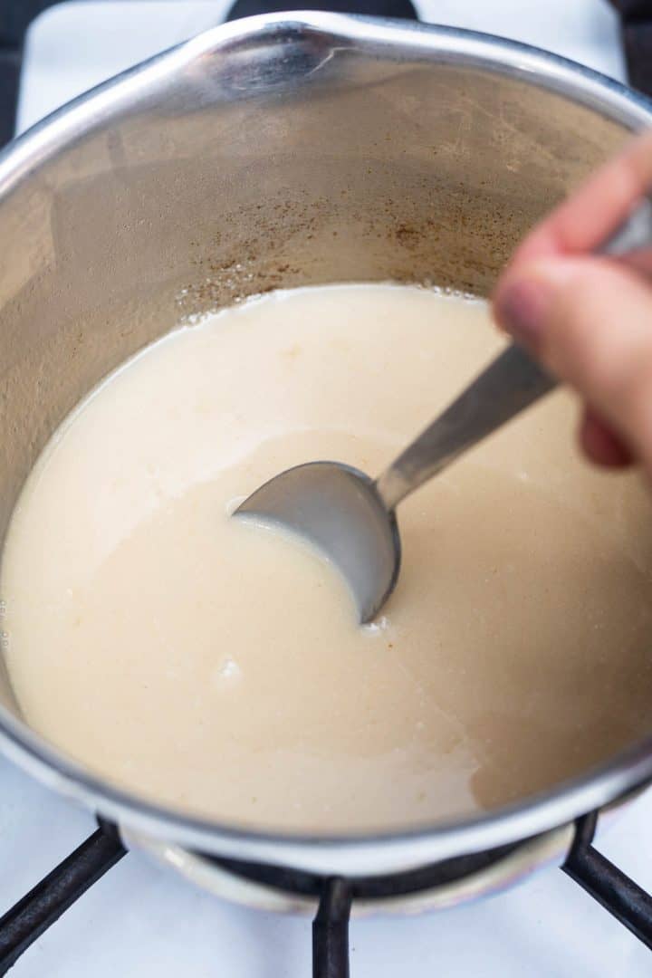 Hand using spoon to stir ice cream on stove