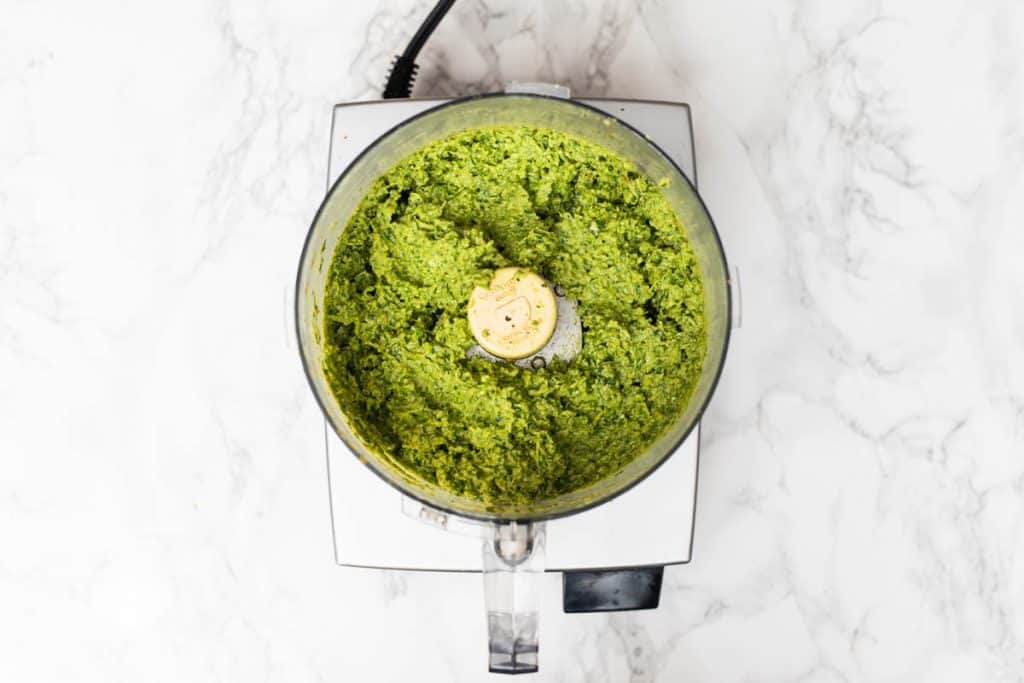 Overhead view of food processor filled with garlic scape pesto