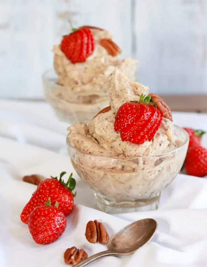 Two bowls of chocolate ice cream with fresh strawberries and pecans