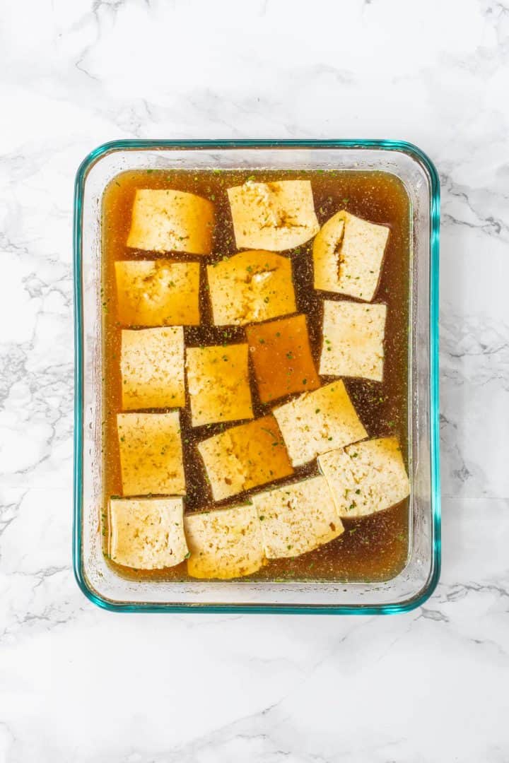 Cubes of tofu in marinade in glass dish