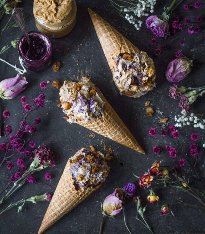 3 blueberry french toast ice cream cones on black surface with fresh purple flowers