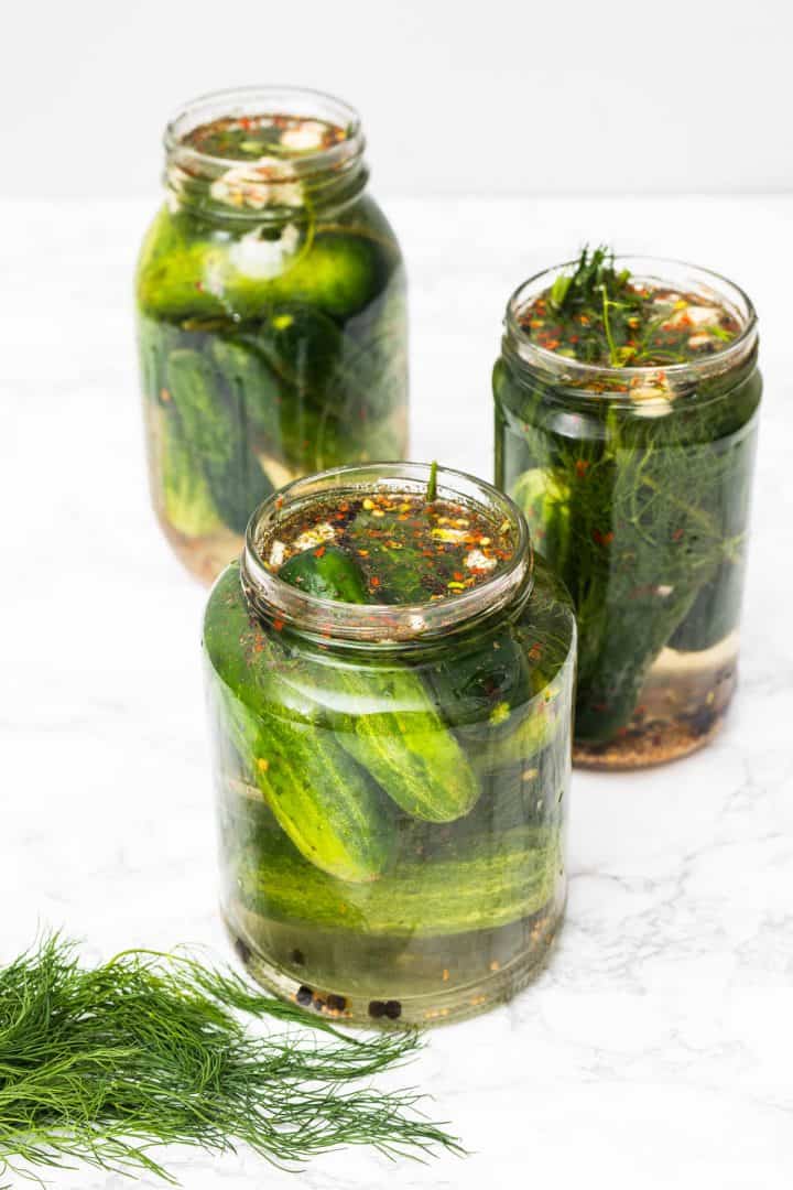 Three jars of homemade dill pickles with fresh dill