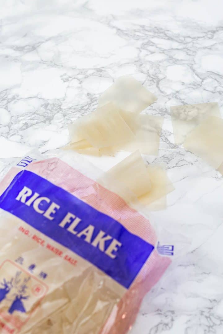 Bag of dry rice flake noodles with pieces spilled onto counter