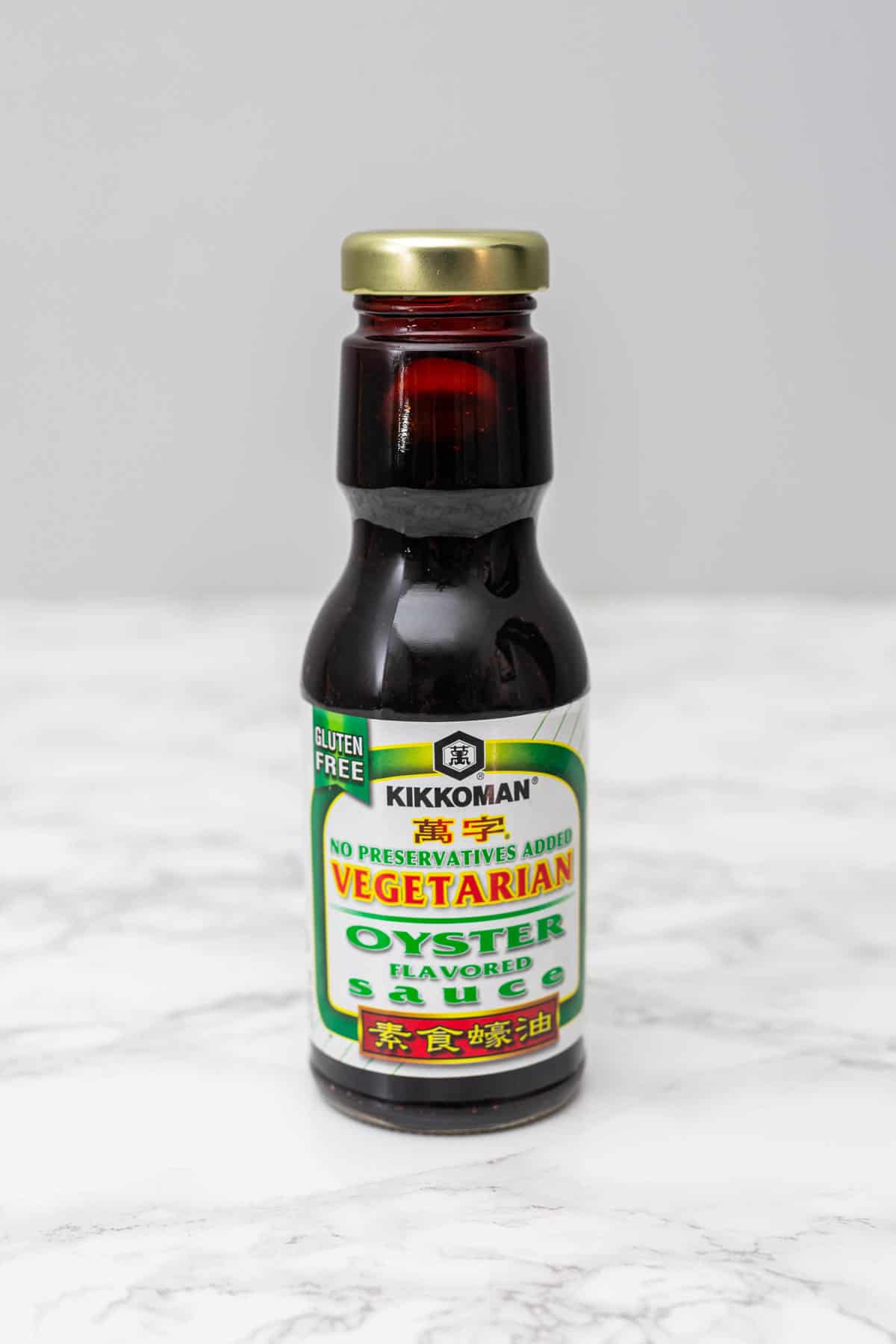 Bottle of Kikkoman Vegetarian Oyster sauce on white marble counter with gray background