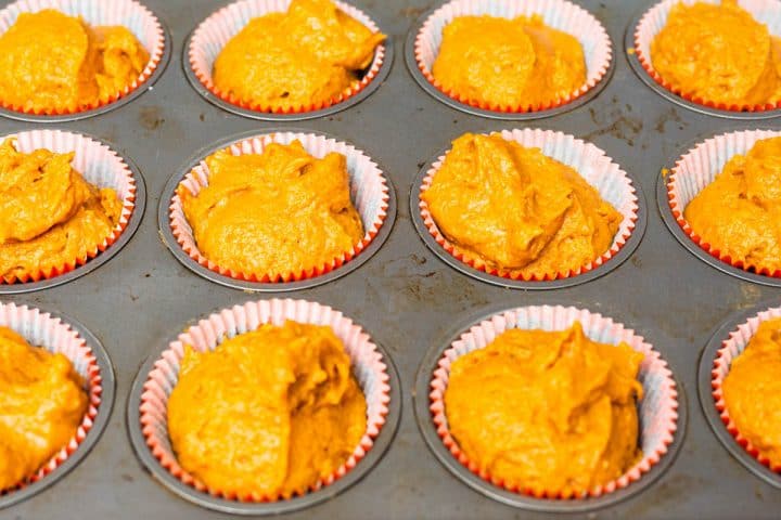 Pumpkin muffin batter in muffin liners in baking tray