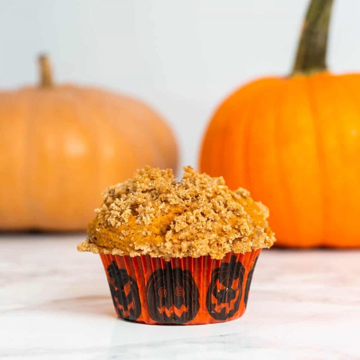 Close up of pumpkin muffin on table with pumpkins in background