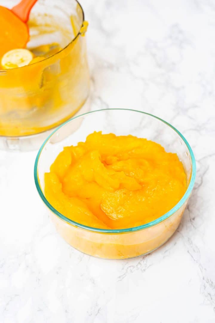 Pie pumpkin puree in glass container with food processor container off to side