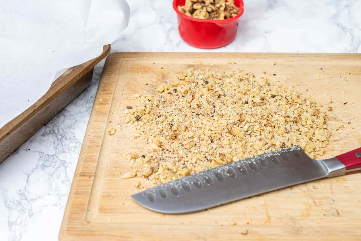Finely chopped walnuts on wooden cutting board with knife