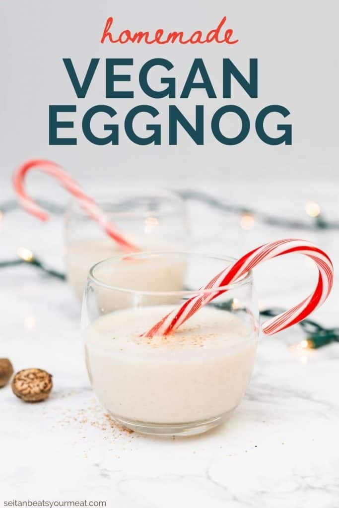 Two glasses of vegan eggnog with candy canes on marble counter with Christmas lights decor with text "Homemade Vegan Eggnog"