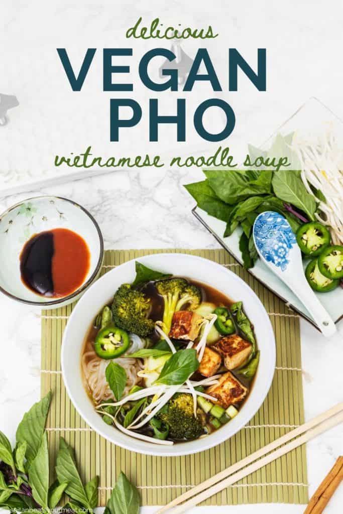 Bowl of vegan pho on bamboo mat with chopsticks with bowl of sauces and plate of toppings off to side with text "Delicious Vegan Pho - Vietnamese noodle soup"