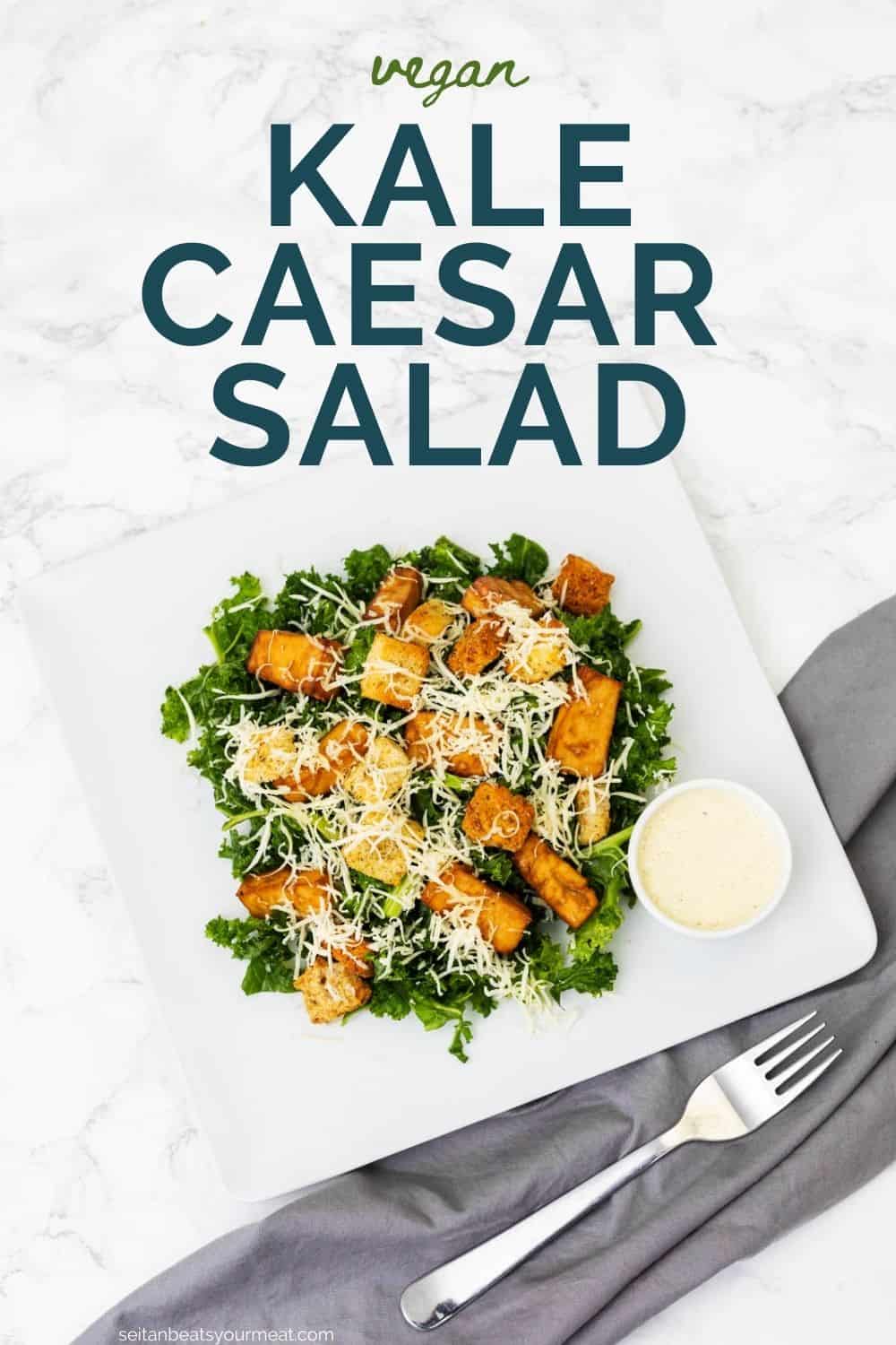 Plate of kale caesar salad with gray cloth napkin and fork with text "Vegan Kale Caesar Salad"